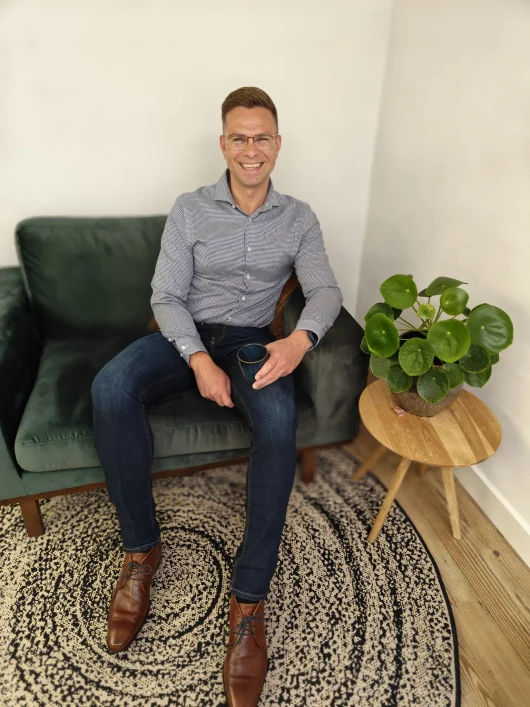 Stijn Metz, Full Stack Developer, zittend met een kop koffie, symboliseert de bereidheid om te helpen en iets te betekenen.