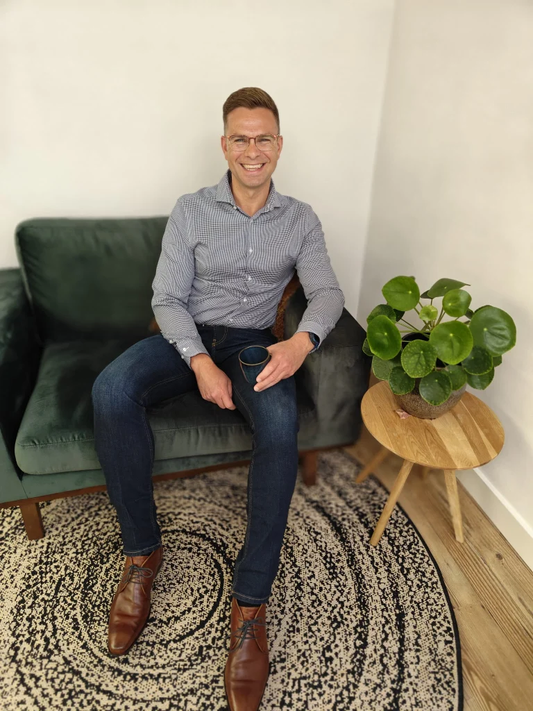 Stijn Metz, Full Stack Developer, zittend met een kop koffie, symboliseert de bereidheid om te helpen en iets te betekenen.